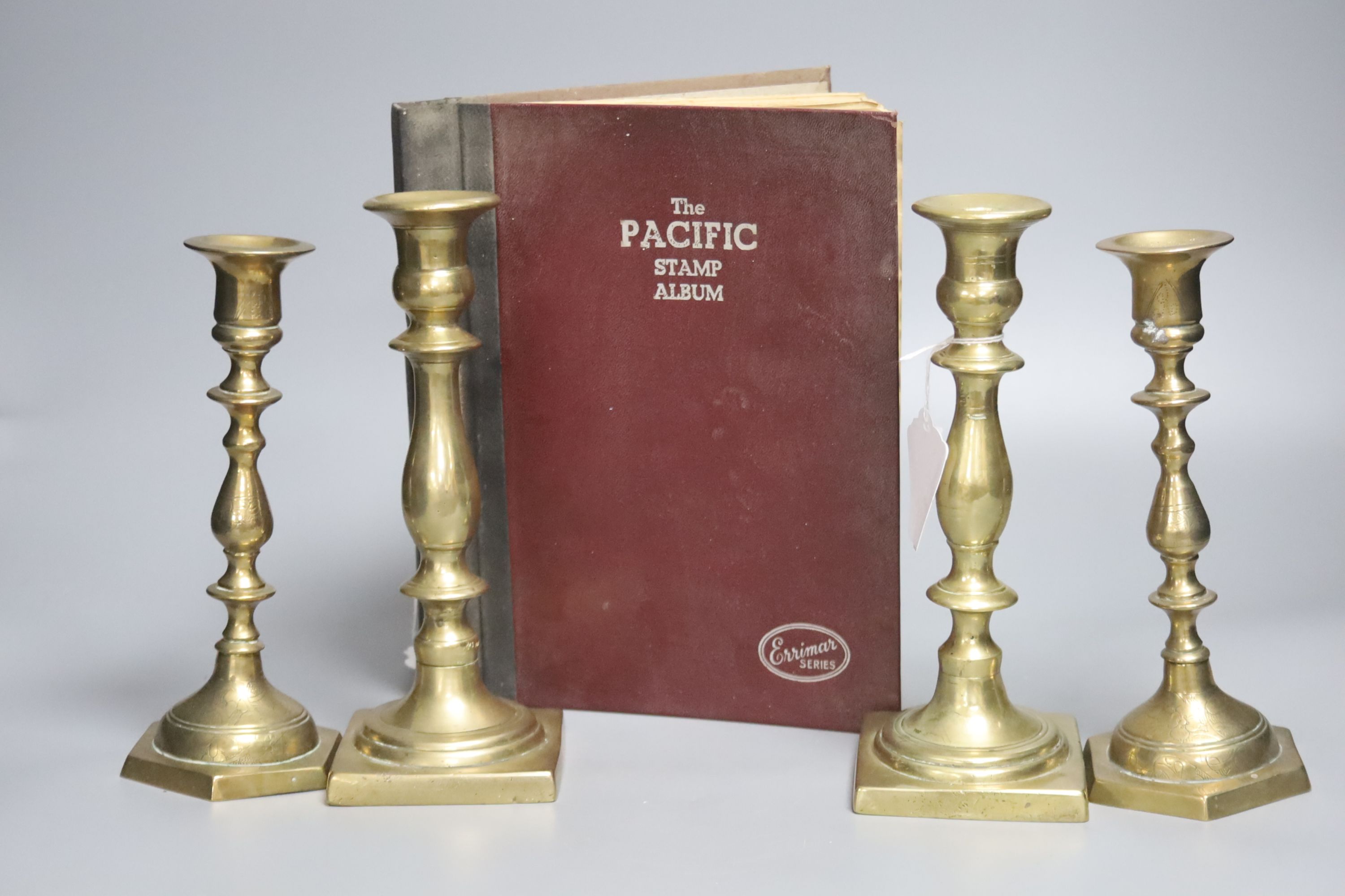 A Pacific stamp album with mixed world stamps, together with two pairs of brass candlesticks (5)